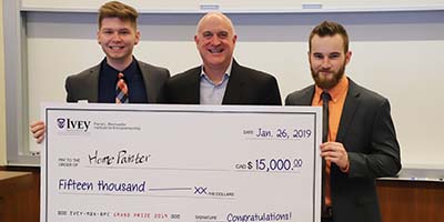 Eric Morse and two students holding a cheque