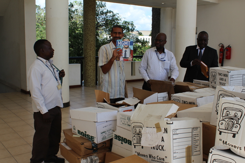 A group of men opening the boxes and showing the books inside