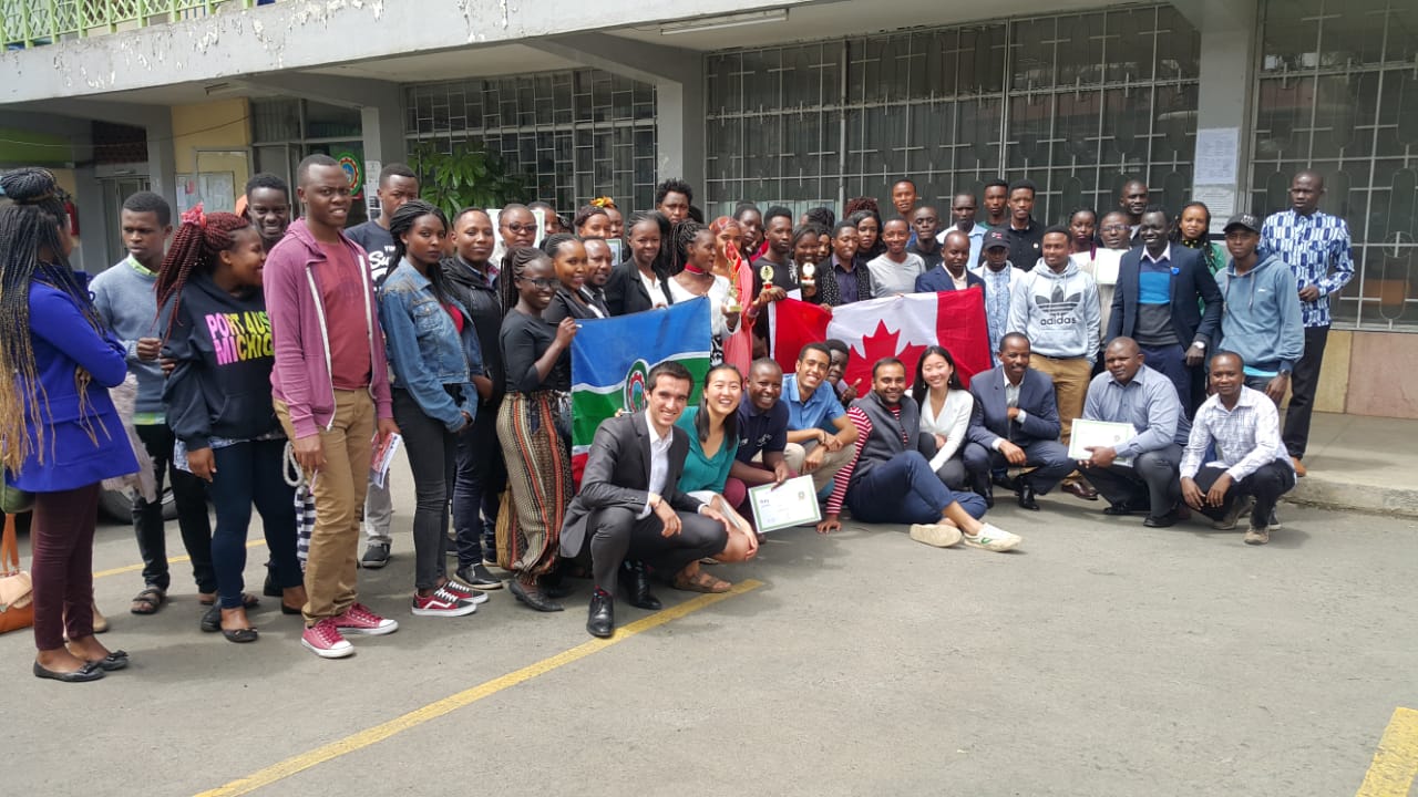 A large group of students posing together holding a Canadian flag