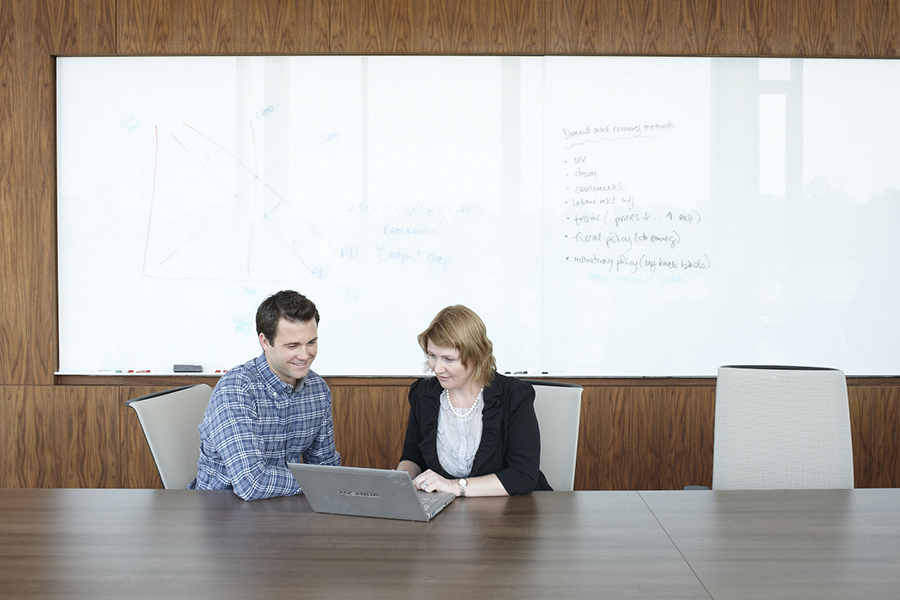 Students looking at a laptop in an Ivey meeting room