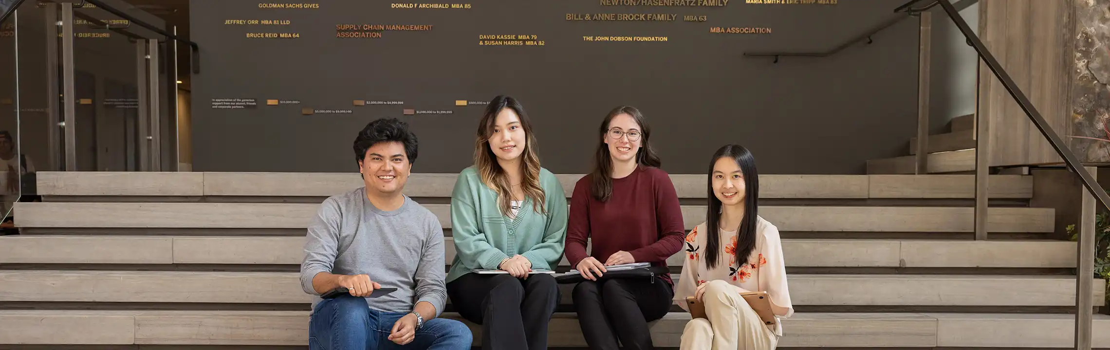 Four students sitting on Ivey's main stairs. 